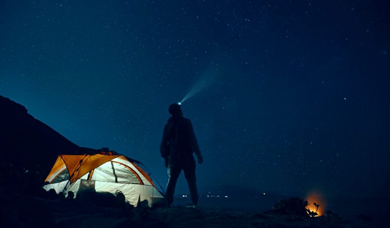 tente camping avec homme debout devant dans la nuit