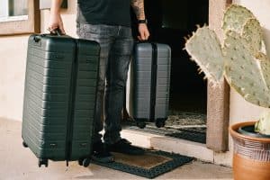 homme avec deux valises devant sa porte d'entrée